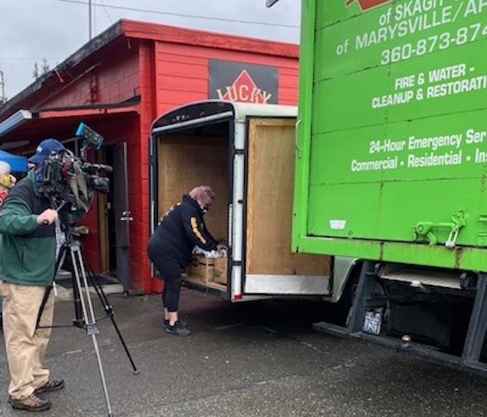 camera man and female standing behind 2 trucks