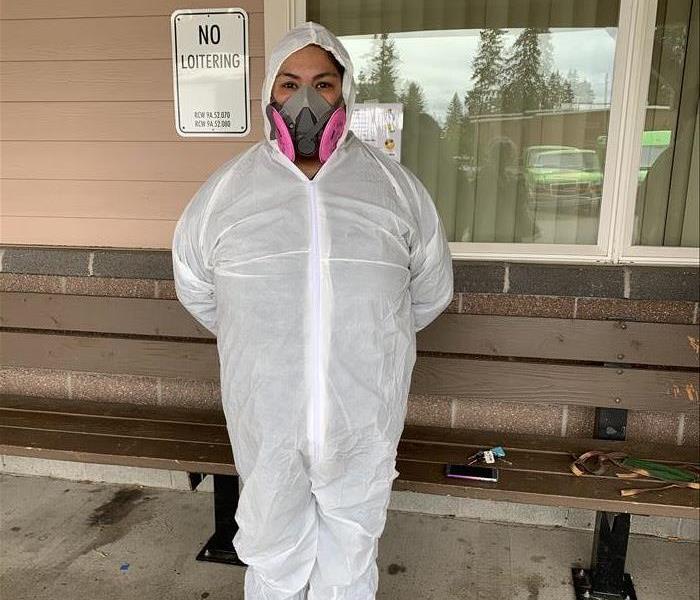 female employee wearing a white PPE suit and face mask