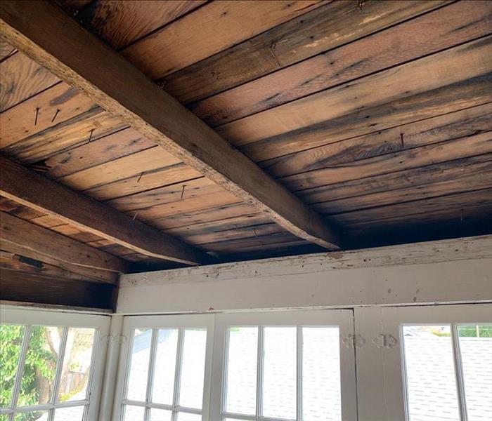 A sunroom ceiling with trim removed to prepare the joists for cleanup