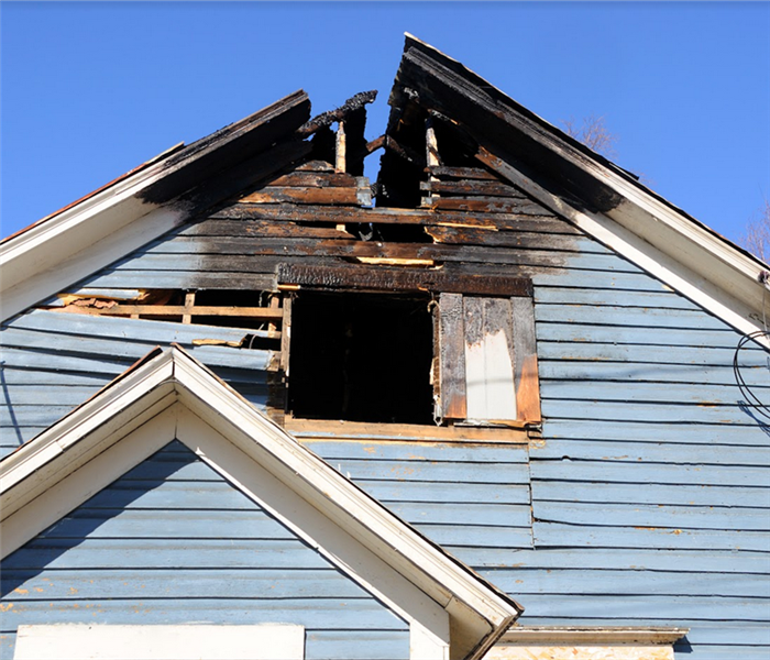 a fire damaged house with a burned roof and siding