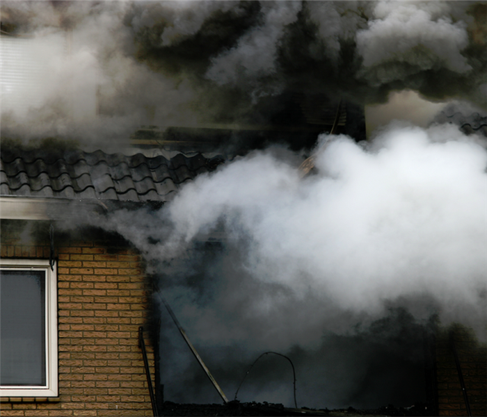 smoke billowing from the windows a house on fire