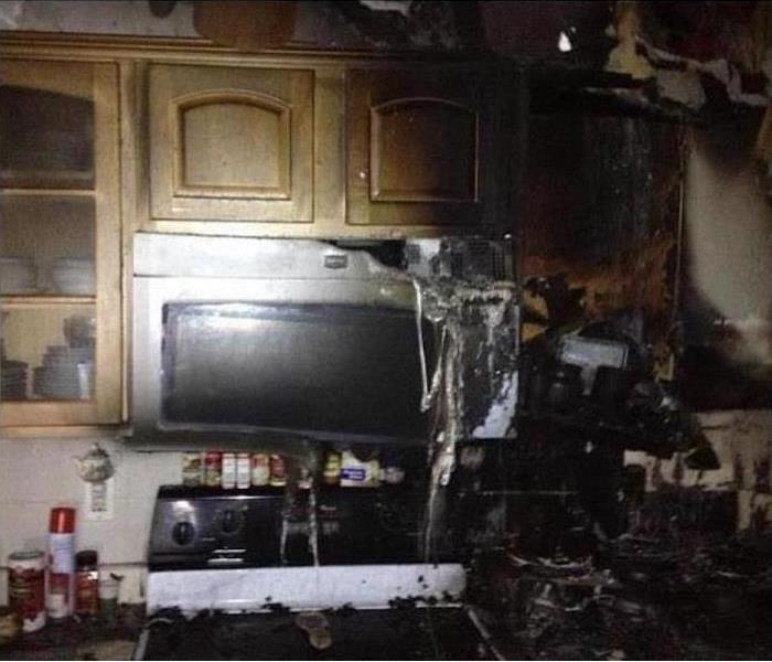 fire damaged kitchen; charred cabinets; melted microwave; debris on stove