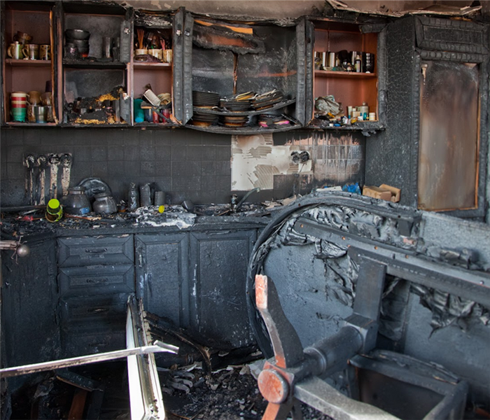 a fire damaged kitchen with soot covering everything and debris everywhere